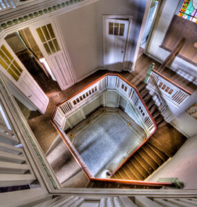 Decaying elegance: Abandoned villa staircase in Belgium, showcasing bygone opulence and neglect.