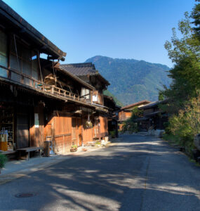Tranquil Japanese village with traditional wooden buildings nestled in lush green mountains.