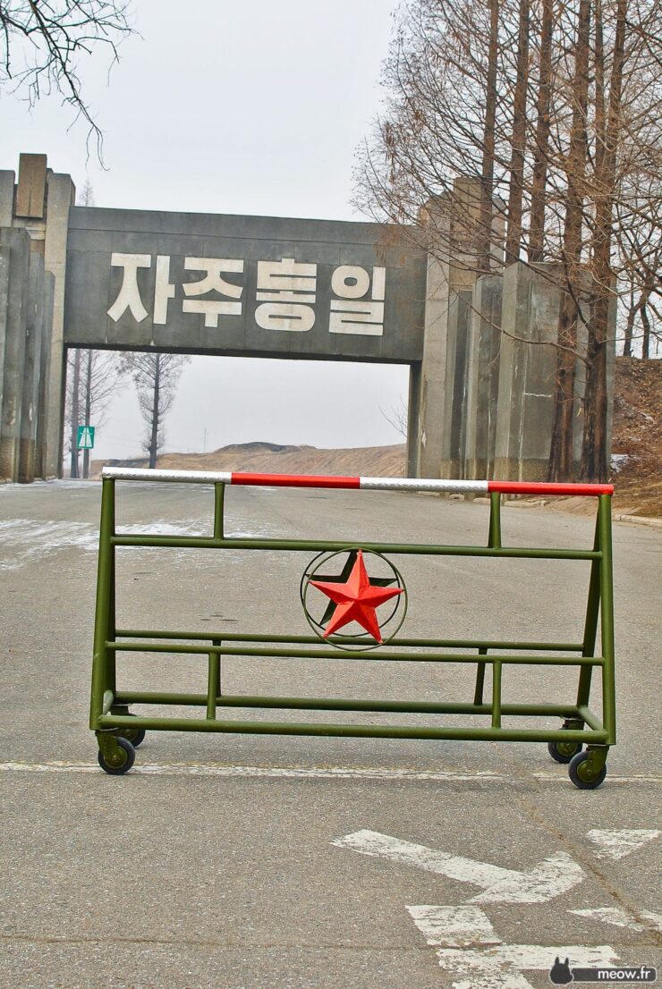 Korean Gate: Jaju Tonghil Entrance in forested area, red and green colors, political significance.
