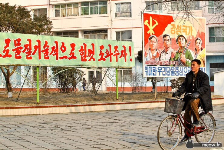 North Korean cityscape with person on bicycle and government building.