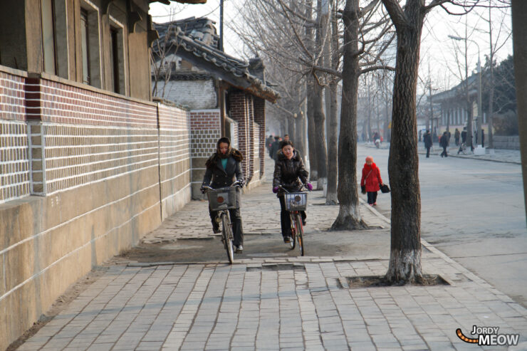 Exploring North Koreas urban streets with cyclists and traditional architecture.