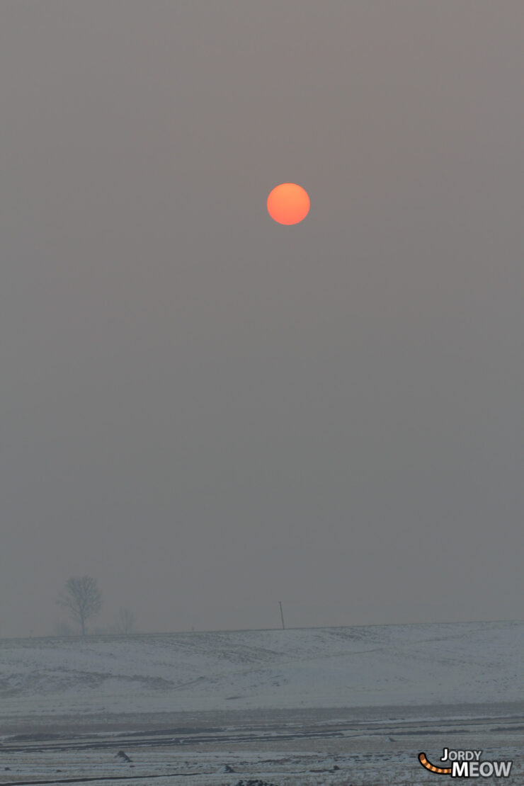 Mysterious North Korea: Fiery sun, snowy landscape, lone tree - evoking isolation and mystery.