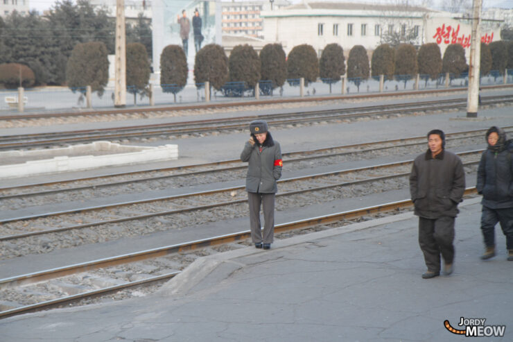 Busy train station scene in urban Pyongyang, North Korea, with commuters in winter clothing.