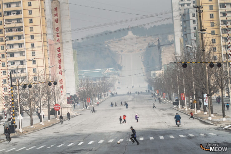 Winter scene in Pyongyang, North Korea with bustling street activity and snowy surroundings.