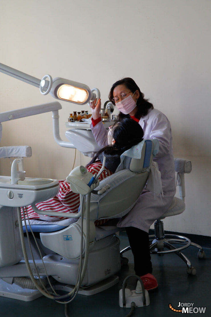 Dentist examining childs teeth in well-equipped Pyongyang dental office, showcasing professional care.