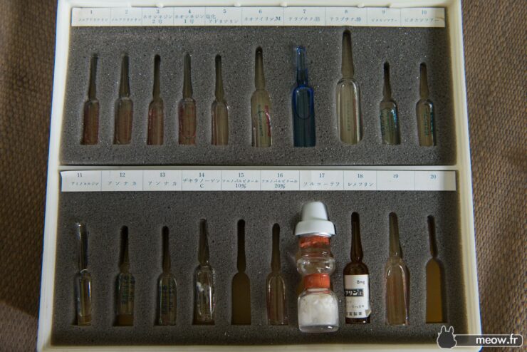 Glass bottles and vials in various sizes and colors neatly displayed in storage case.