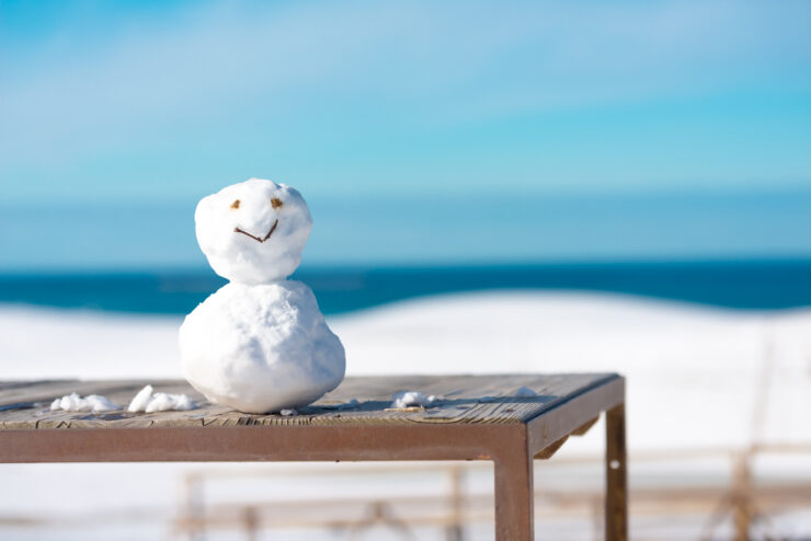 Enchanting Tottori Sand Dunes landscape with a whimsical snowman and serene ocean view.