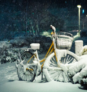 Tranquil snowy night in Roppongi, Tokyo, with vibrant yellow bike covered in snow.