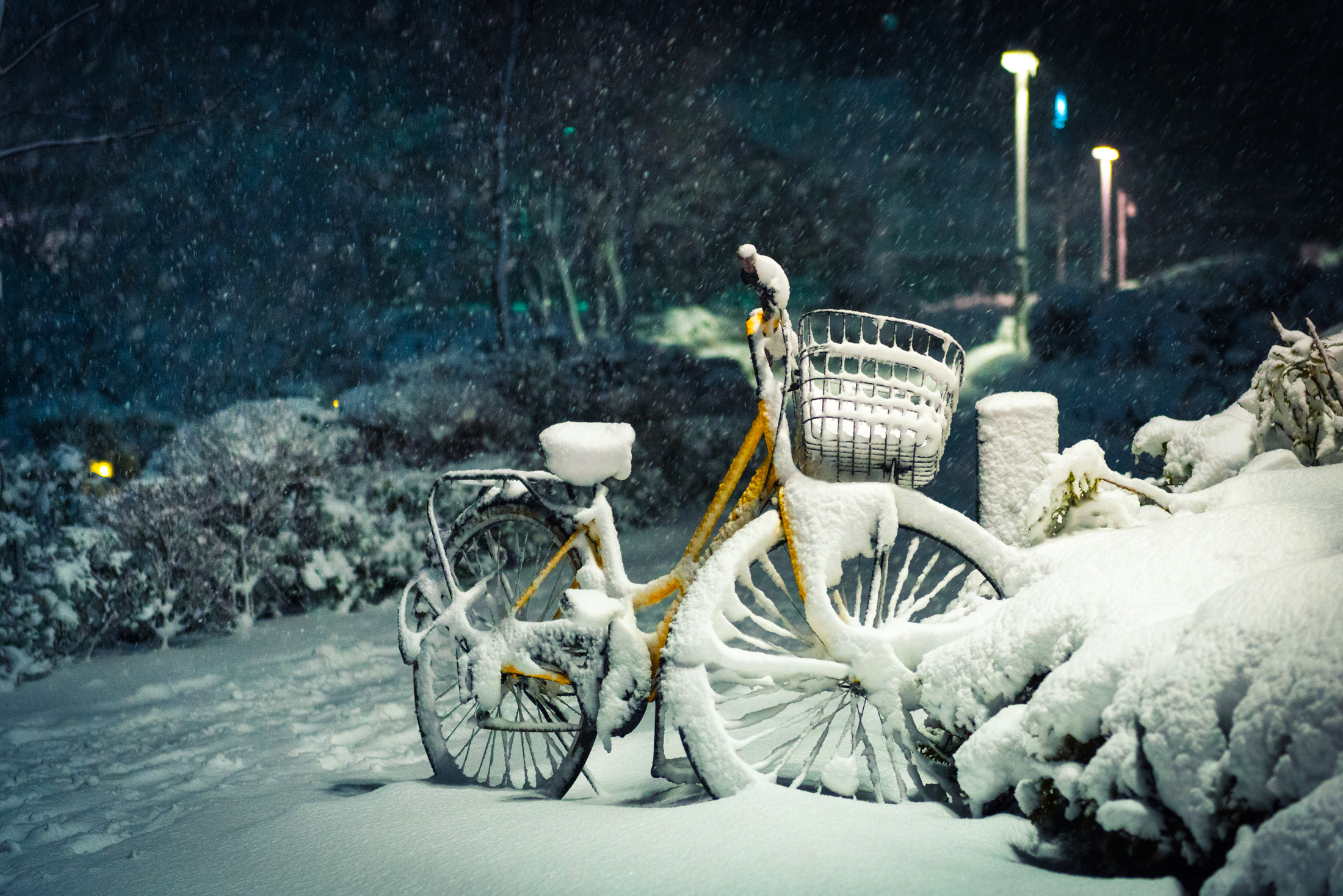 Tranquil snowy night in Roppongi, Tokyo, with vibrant yellow bike covered in snow.