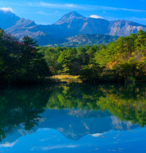 Serene Goshikinuma Lake in Japan surrounded by lush forests and vibrant autumnal foliage.