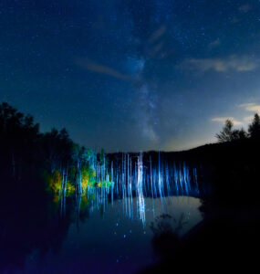 Mystical night scene at Blue Pond in Biei, Hokkaido, with colorful celestial lights.