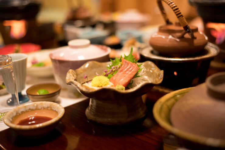 Japanese dining experience with hot pot, salmon slices, and pickled vegetables at Kanaguya Ryokan.