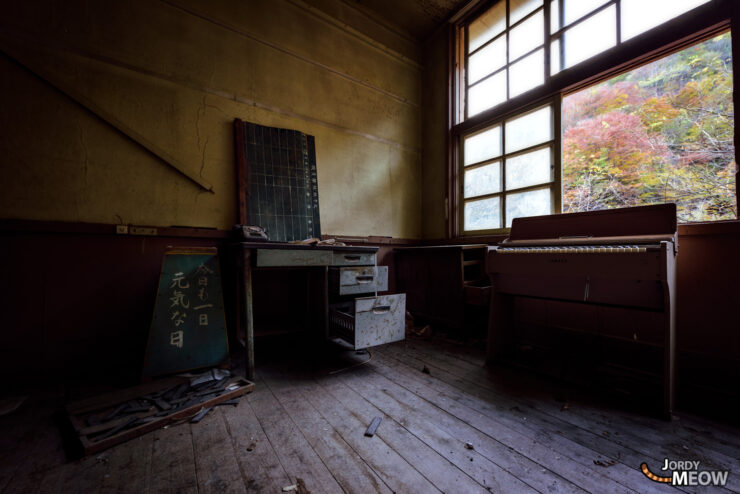 Abandoned room with autumn view, showcasing decayed objects and vibrant foliage.