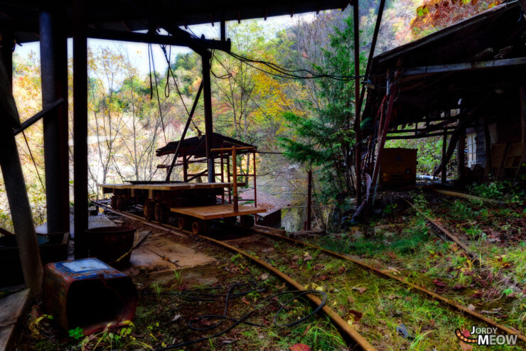 Abandoned Nichitsu Mine in Autumn Forest - Tranquil scene of decayed industrial ruins amidst nature.