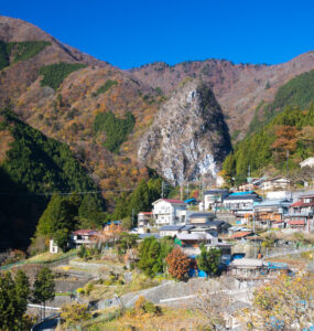Inamura Rock: Majestic autumn landscape with vibrant foliage and peaceful village in Japan.
