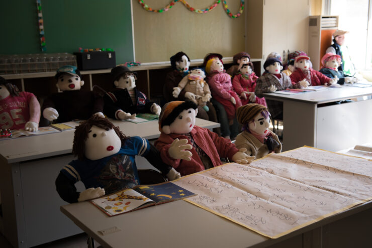 Dolls in Classroom: Nagoro Village - Lifelike dolls in festive classroom setting.