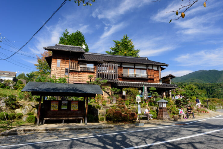 Explore the historic charm of Magome-Juku in Japan with wooden buildings and lush greenery.